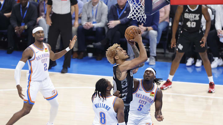 Oct 30, 2024; Oklahoma City, Oklahoma, USA; San Antonio Spurs forward Jeremy Sochan (10) shoots between Oklahoma City Thunder forward Jalen Williams (8) and guard Luguentz Dort (5) during the first quarter at Paycom Center. Mandatory Credit: Alonzo Adams-Imagn Images Oct 30, 2024; Oklahoma City, Oklahoma, USA; San Antonio Spurs forward Jeremy Sochan (10) shoots between Oklahoma City Thunder forward Jalen Williams (8) and guard Luguentz Dort (5) during the first quarter at Paycom Center. Mandatory Credit: Alonzo Adams-Imagn Images