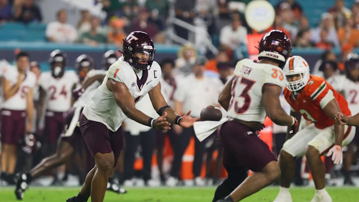 Sep 27, 2024; Miami Gardens, Florida, USA; Virginia Tech Hokies quarterback Kyron Drones (1) tosses the football to running back Bhayshul Tuten (33) against the Miami Hurricanes during the third quarter at Hard Rock Stadium. Mandatory Credit: Sam Navarro-Imagn Images Sep 27, 2024; Miami Gardens, Florida, USA; Virginia Tech Hokies quarterback Kyron Drones (1) tosses the football to running back Bhayshul Tuten (33) against the Miami Hurricanes during the third quarter at Hard Rock Stadium. Mandatory Credit: Sam Navarro-Imagn Images