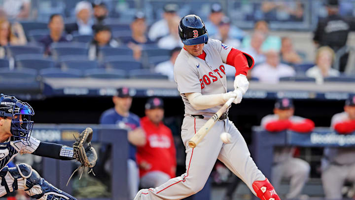 A baseball player in a white and red uniform swinging a white bat toward a white baseball
