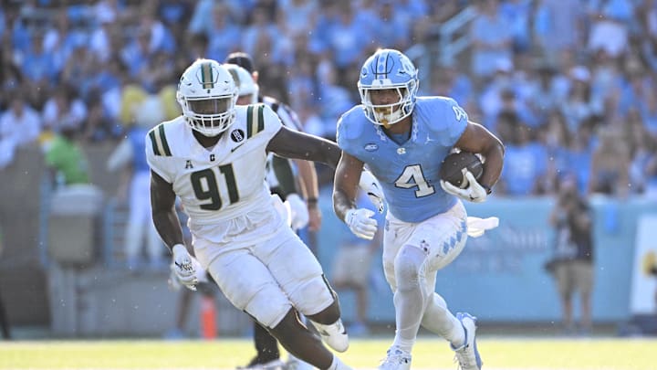 Sep 7, 2024; Chapel Hill, North Carolina, USA; North Carolina Tar Heels running back Caleb Hood (4) with the ball as Charlotte 49ers defensive lineman Dre Butler (91) defends in the third quarter at Kenan Memorial Stadium. 