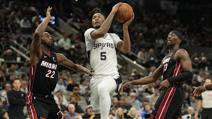 Oct 30, 2025; San Antonio, Texas, USA; San Antonio Spurs guard Stephon Castle (5) drives to the basket between Miami Heat forwards Andrew Wiggins (22) and Bam Adebayo (13) during the first half at Frost Bank Center. Mandatory Credit: Scott Wachter-Imagn Images