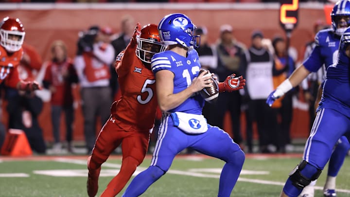 Nov 9, 2024; Salt Lake City, Utah, USA; Brigham Young Cougars quarterback Jake Retzlaff (12) is sacked by Utah Utes cornerback Zemaiah Vaughn (5) during the second half at Rice-Eccles Stadium. Mandatory Credit: Rob Gray-Imagn Images