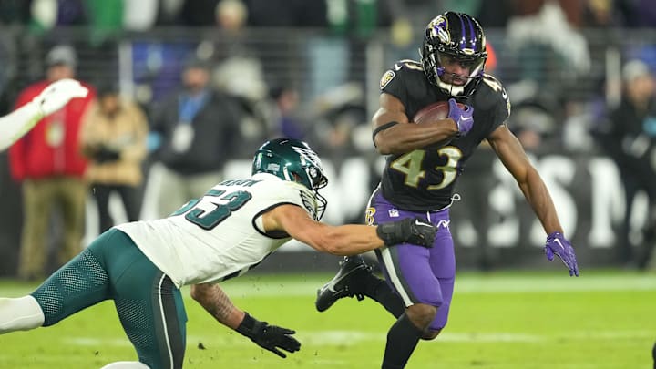 Dec 1, 2024; Baltimore, Maryland, USA; Baltimore Ravens running back Justice Hill (43) runs for a third quarter gain defended by Philadelphia Eagles linebacker Zack Baun (53) at M&T Bank Stadium. Mandatory Credit: Mitch Stringer-Imagn Images