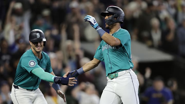 Jun 1, 2024; Seattle, Washington, USA;  Seattle Mariners center fielder Julio Rodríguez, right, is greeted at home by Seattle Mariners third baseman Dylan Moore, left, scoring on a double by Cal Raleigh against the Los Angeles Angels during the sixth inning at T-Mobile Park. Mandatory Credit: John Froschauer-USA TODAY Sports
