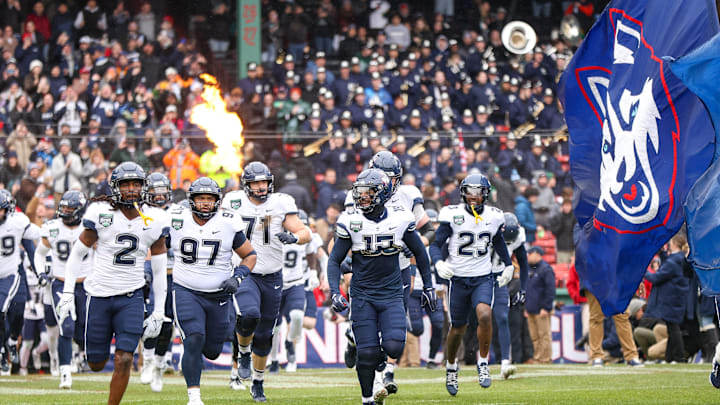 UConn's Rante Jones, left, and Tui Faumuina-Brown lead the team out of the tunnel during the third annual Wasabi Fenway Bowl against North Carolina at Fenway Park on Saturday, Dec. 28, 2024.