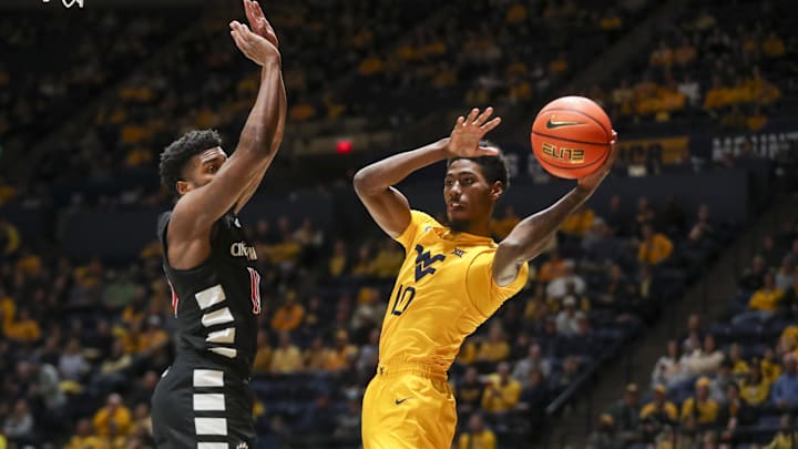Feb 19, 2025; Morgantown, West Virginia, USA;West Virginia Mountaineers guard Sencire Harris (10) passes around Cincinnati Bearcats guard Josh Reed (10) during the first half  at WVU Coliseum. Mandatory Credit: Ben Queen-Imagn Images