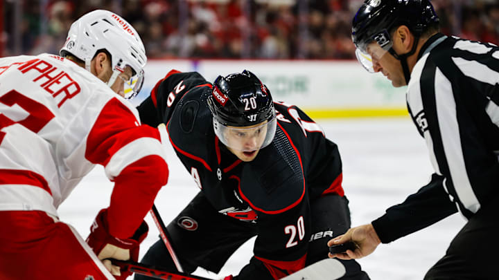 Detroit Red Wings forward J.T. Compher and Carolina Hurricanes forward Martin Necas come together for a face-off.