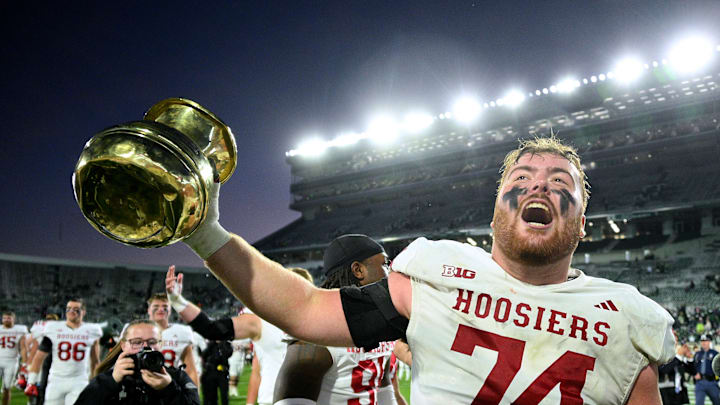 Nov 2, 2024; East Lansing, Michigan, USA;  Indiana Hoosiers offensive lineman Bray Lynch (74) holds up The Old Brass Spittoon after beating Michigan State at Spartan Stadium. Mandatory Credit: Dale Young-Imagn Images