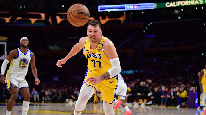 Apr 3, 2025; Los Angeles, California, USA; Los Angeles Lakers guard Luka Doncic (77) plays for the ball against the Golden State Warriors during the second half at Crypto.com Arena. Mandatory Credit: Gary A. Vasquez-Imagn Images
