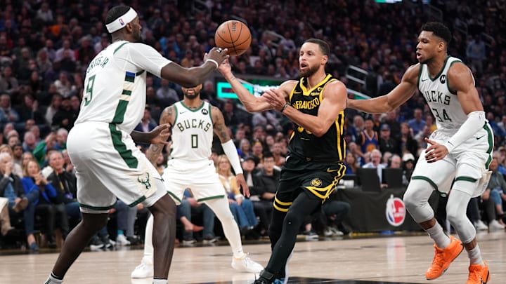 Mar 6, 2024; San Francisco, California, USA; Golden State Warriors guard Stephen Curry (30) passes the ball between Milwaukee Bucks forward Bobby Portis (9) and forward Giannis Antetokounmpo (34) in the third quarter at the Chase Center. Mandatory Credit: Cary Edmondson-Imagn Images