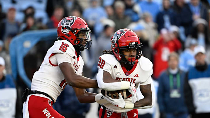 Nov 30, 2024; Chapel Hill, North Carolina, USA; North Carolina State Wolfpack quarterback CJ Bailey (16) hands the ball off to running back Hollywood Smothers (20) the ball in the first quarter at Kenan Memorial Stadium. Mandatory Credit: Bob Donnan-Imagn Images