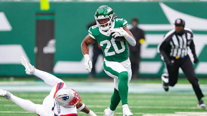 Dec 28, 2025; East Rutherford, New Jersey, USA; New York Jets running back Breece Hall (20) carries the ball asNew England Patriots linebacker K'Lavon Chaisson (44) pursues during the first half at MetLife Stadium. Mandatory Credit: Vincent Carchietta-Imagn Images