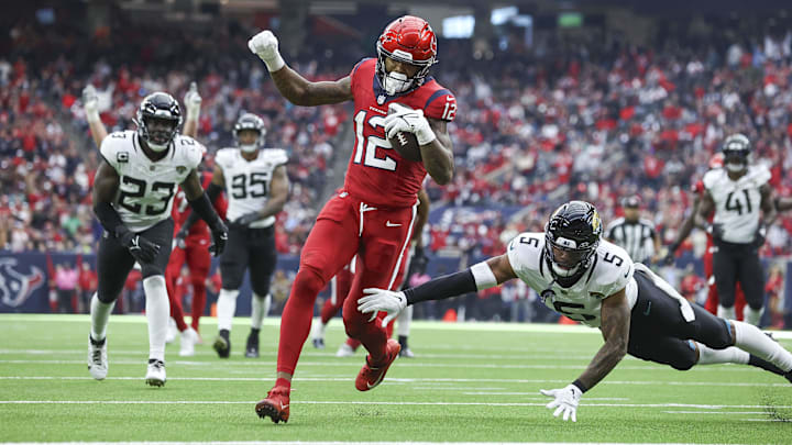 Nov 26, 2023; Houston, Texas, USA; Houston Texans wide receiver Nico Collins (12) runs with the ball and scores a touchdown as Jacksonville Jaguars safety Andre Cisco (5) defends during the fourth quarter at NRG Stadium. Mandatory Credit: Troy Taormina-Imagn Images