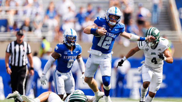 Sep 21, 2024; Lexington, Kentucky, USA; Kentucky Wildcats quarterback Brock Vandagriff (12) jumps over Ohio Bobcats linebacker Stellan Bowman (30) during the fourth quarter at Kroger Field. Mandatory Credit: Jordan Prather-Imagn Images