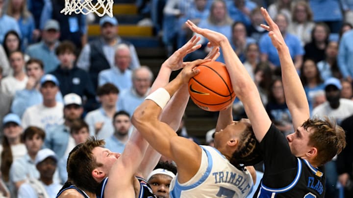 Mar 8, 2025; Chapel Hill, North Carolina, USA; North Carolina Tar Heels guard Seth Trimble (7) with the ball as Duke Blue Devils guard Kon Knueppel (7) and forward Cooper Flagg (2) defend in the second half at Dean E. Smith Center. Mandatory Credit: Bob Donnan-Imagn Images