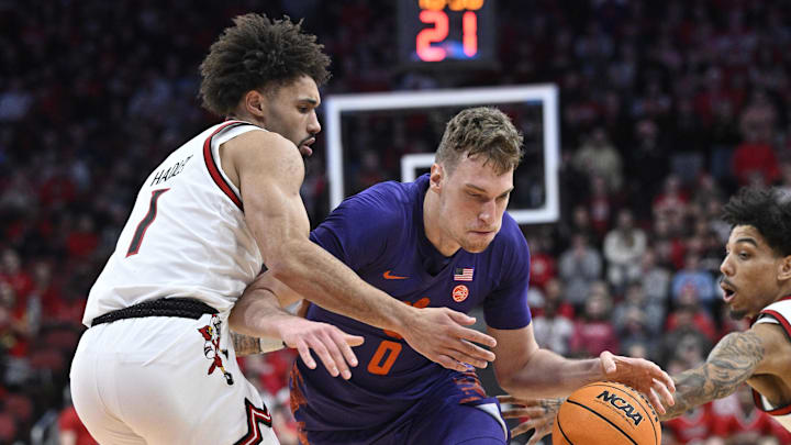 Jan 7, 2025; Louisville, Kentucky, USA; Clemson Tigers center Viktor Lakhin (0) drives to the basket against Louisville Cardinals guard J'Vonne Hadley (1) during the first half at KFC Yum! Center. Mandatory Credit: Jamie Rhodes-Imagn Images