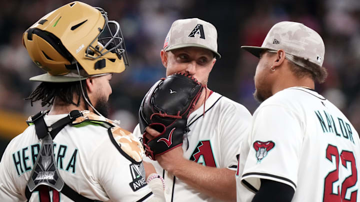 Arizona Diamondbacks pitcher Merrill Kelly (29) chats with infielder Josh Naylor (22) and catcher Jose Herrera (11) as he pitches against the Colorado Rockies at Chase Field in Phoenix on May 18, 2025.