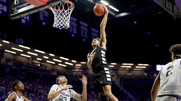 Dec 30, 2024; Manhattan, Kansas, USA; Cincinnati Bearcats guard Dan Skillings Jr. (0) dunks the ball against Kansas State Wildcats guard Coleman Hawkins (33) and guard David N'Guessan (1) during the first half at Bramlage Coliseum. Mandatory Credit: Jay Biggerstaff-Imagn Images Dec 30, 2024; Manhattan, Kansas, USA; Cincinnati Bearcats guard Dan Skillings Jr. (0) dunks the ball against Kansas State Wildcats guard Coleman Hawkins (33) and guard David N'Guessan (1) during the first half at Bramlage Coliseum. Mandatory Credit: Jay Biggerstaff-Imagn Images