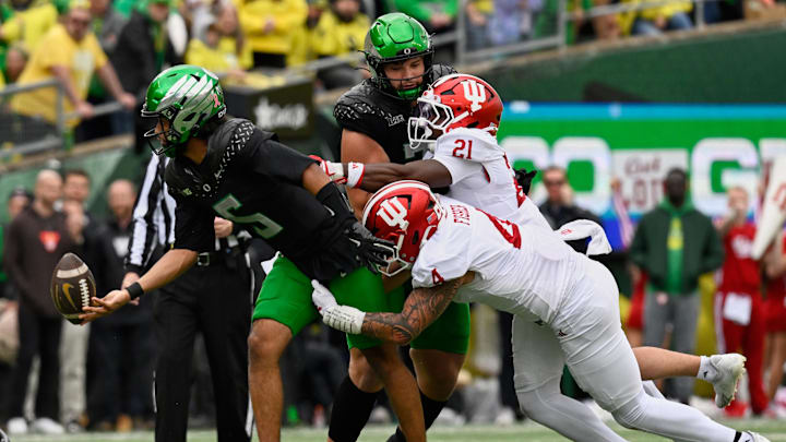 Oct 11, 2025; Eugene, Oregon, USA; Oregon Ducks quarterback Dante Moore (5) tosses the ball to a teammate as he is tackled by Indiana Hoosiers linebacker Aiden Fisher (4) during the second quarter at Autzen Stadium. Mandatory Credit: Troy Wayrynen-Imagn Images
