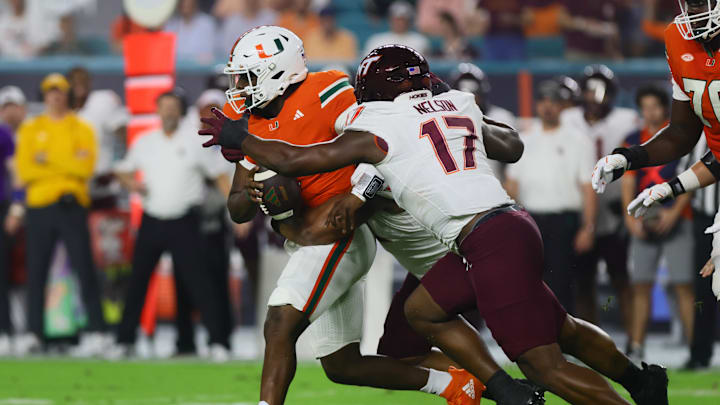 Sep 27, 2024; Miami Gardens, Florida, USA; Miami Hurricanes quarterback Cam Ward (1) fumbles the football after a tackle by Virginia Tech Hokies defensive lineman Cole Nelson (17) during the first quarter at Hard Rock Stadium. Mandatory Credit: Sam Navarro-Imagn Images