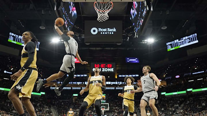 Dec 18, 2025; San Antonio, Texas, USA; San Antonio Spurs guard Stephon Castle (5) dunks over Washington Wizards forward Alex Sarr (20) during the first half at Frost Bank Center. Mandatory Credit: Scott Wachter-Imagn Images