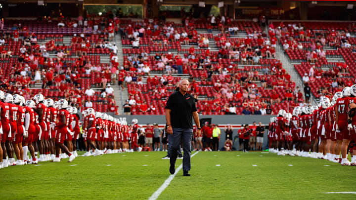 Aug 29, 2024; Raleigh, North Carolina, USA; North Carolina State Wolfpack head coach Dave Doeren between his players before the first half of the game against Western Carolina Catamounts at Carter-Finley Stadium. Mandatory Credit: Jaylynn Nash-Imagn Images