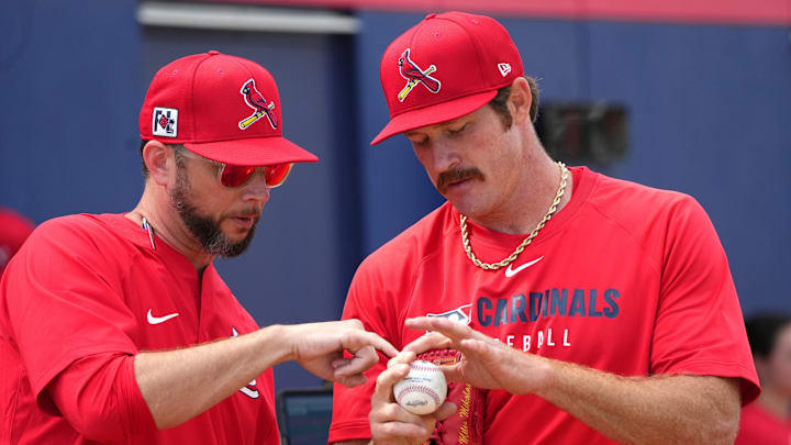 Feb 12, 2025; Jupiter, FL, USA;  St. Louis Cardinals St. Louis Cardinals pitcher Miles Mikolas, right, goes over his grip with pitching coach Dusty Blake during Spring Training. Mandatory Credit: Jim Rassol-Imagn Images