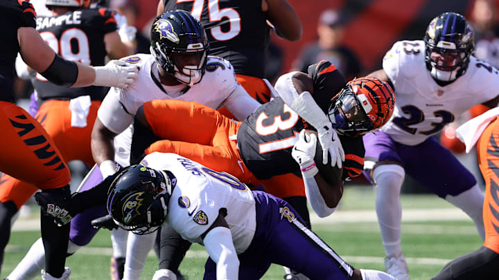 Oct 6, 2024; Cincinnati, Ohio, USA; Cincinnati Bengals running back Zack Moss (31) runs the ball as Baltimore Ravens linebacker Roquan Smith (0) and defensive tackle Nnamdi Madubuike (92) make the tackle during the first quarter at Paycor Stadium. Mandatory Credit: Joseph Maiorana-Imagn Images