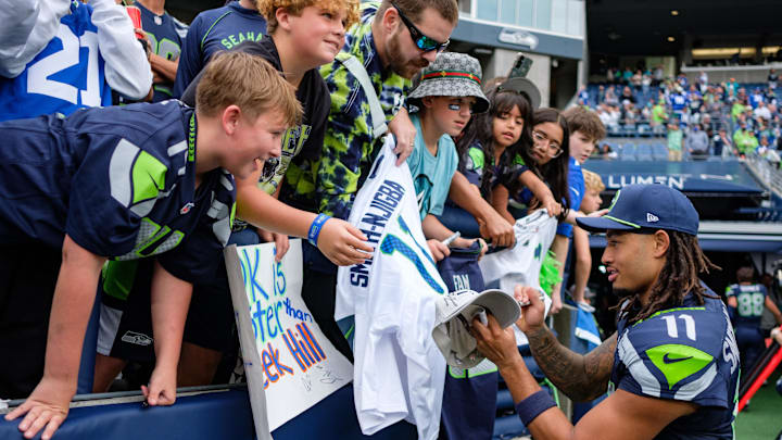 Sep 22, 2024; Seattle, Washington, USA; Seattle Seahawks wide receiver Jaxon Smith-Njigba (11) autographs a fan’s poster after the game against Miami Dolphins at Lumen Field. Mandatory Credit: Kevin Ng-Imagn Images