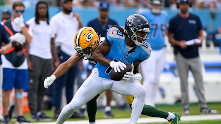 Sep 22, 2024; Nashville, Tennessee, USA;  Green Bay Packers cornerback Eric Stokes (21) tackles Tennessee Titans wide receiver DeAndre Hopkins (10) after a made catch during the first half at Nissan Stadium. Mandatory Credit: Steve Roberts-Imagn Images