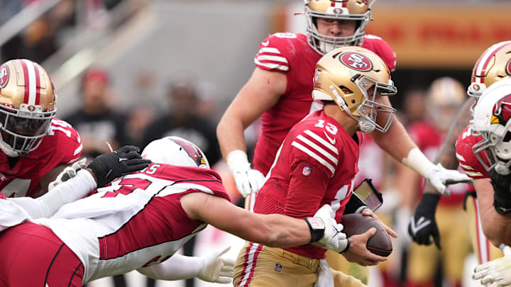 Arizona Cardinals linebacker Cameron Thomas (left) tries to tackle San Francisco 49ers quarterback Brock Purdy (right)