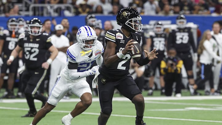 Dec 28, 2024; San Antonio, TX, USA; Colorado Buffaloes quarterback Shedeur Sanders (2) runs with the ball as Brigham Young Cougars cornerback Evan Johnson (21) attempts to make a tackle during the third quarter at Alamodome. Mandatory Credit: Troy Taormina-Imagn Images