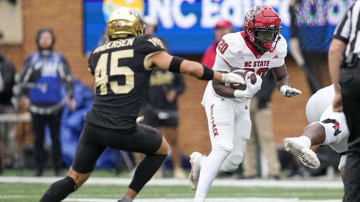 Nov 11, 2023; Winston-Salem, North Carolina, USA; North Carolina State Wolfpack running back Kendrick Raphael (20) tries to avoid Wake Forest Demon Deacons defensive back Nick Andersen (45) during the first half at Allegacy Federal Credit Union Stadium. Mandatory Credit: Jim Dedmon-Imagn Images