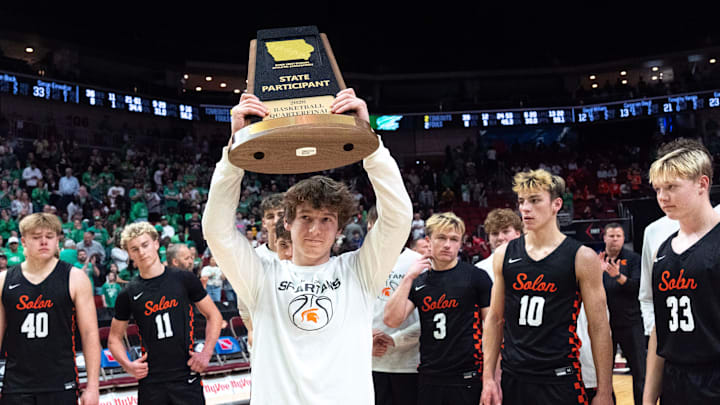 Solon’s Tyler Greazel (2) lifts the state participant trophy March 9, 2026 after a Iowa high school boys state basketball tournament quarterfinal game against the Storm Lake Tornadoes at the Casey’s Center in Des Moines, Iowa.