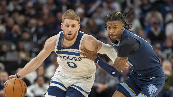Jan 11, 2025; Minneapolis, Minnesota, USA; Minnesota Timberwolves guard Donte DiVincenzo (0) dribbles the ball against Memphis Grizzlies guard Ja Morant (12) in the first half at Target Center. Mandatory Credit: Jesse Johnson-Imagn Images