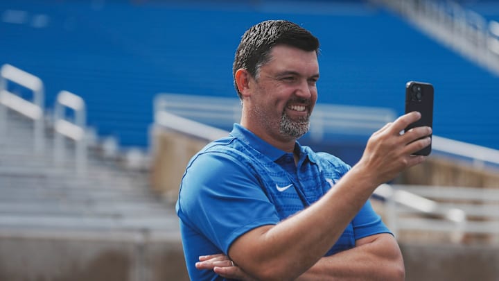 Kentucky defensive coordinator Brad White takes in the scene with his phone during media day at Kroger Field Friday. August 2, 2024 in Lexington.