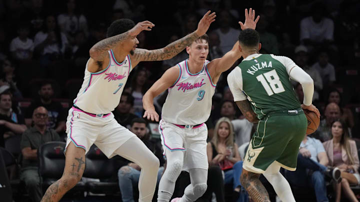 Apr 5, 2025; Miami, Florida, USA;  Milwaukee Bucks forward Kyle Kuzma (18) looks to take a shot as Miami Heat and guard Pelle Larsson (9) and center Kel'el Ware (7) defend on the play during the first half at Kaseya Center. Mandatory Credit: Jim Rassol-Imagn Images