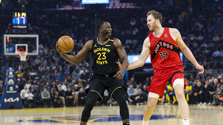 Mar 20, 2025; San Francisco, California, USA; Golden State Warriors forward Draymond Green (23) passes as Toronto Raptors center Jakob Poeltl (19) defends during the first quarter at Chase Center. Mandatory Credit: John Hefti-Imagn Images