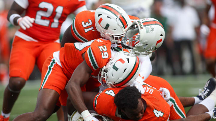 Nov 9, 2024; Atlanta, Georgia, USA; Georgia Tech Yellow Jackets wide receiver Malik Rutherford (8) is tackled by Miami Hurricanes defensive back OJ Frederique Jr. (29) and linebacker Wesley Bissainthe (31) and defensive lineman Rueben Bain Jr. (4) in the second quarter at Bobby Dodd Stadium at Hyundai Field. Mandatory Credit: Brett Davis-Imagn Images
