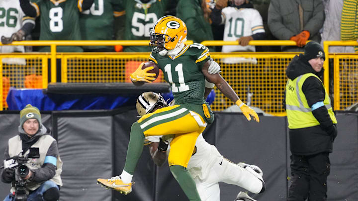 Dec 23, 2024; Green Bay, Wisconsin, USA;  Green Bay Packers wide receiver Jayden Reed (11) is tackled by New Orleans Saints safety Ugo Amadi (0) after catching a pass during the fourth quarter at Lambeau Field. Mandatory Credit: Jeff Hanisch-Imagn Images
