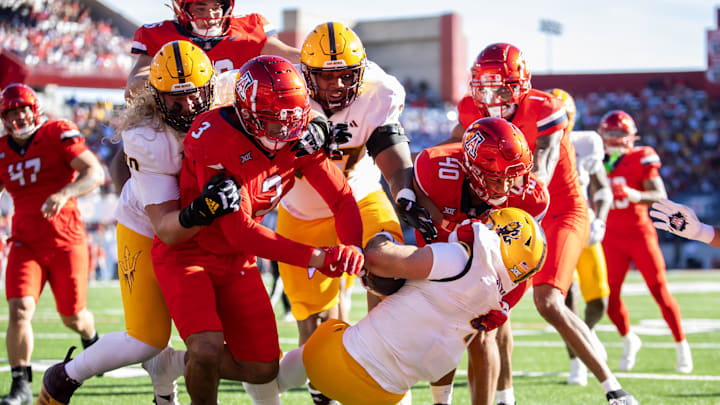 Nov 30, 2024; Tucson, Arizona, USA; Arizona State Sun Devils running back Cam Skattebo (4) is tackled by Arizona Wildcats defensive lineman Tre Smith (3) and linebacker Jared Small (40) in the first half during the Territorial Cup at Arizona Stadium. Mandatory Credit: Mark J. Rebilas-Imagn Images
Nov 30, 2024; Tucson, Arizona, USA; Arizona State Sun Devils running back Cam Skattebo (4) is tackled by Arizona Wildcats defensive lineman Tre Smith (3) and linebacker Jared Small (40) in the first half during the Territorial Cup at Arizona Stadium. Mandatory Credit: Mark J. Rebilas-Imagn Images