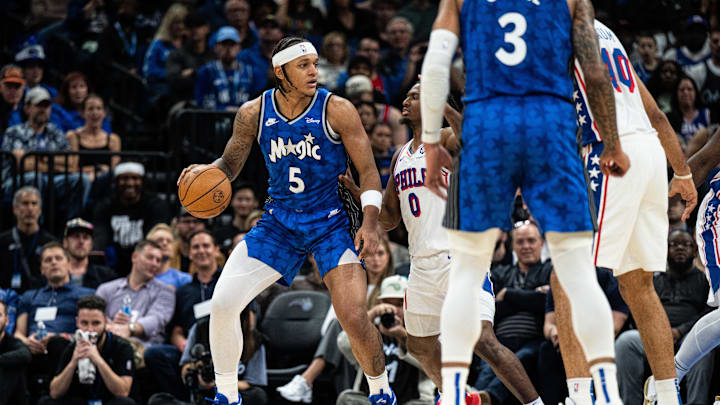 Jan 19, 2024; Orlando, Florida, USA; Orlando Magic forward Paolo Banchero (5) dribbles the ball against Philadelphia 76ers point guard Tyrese Maxey (0) in the first quarter at KIA Center. Mandatory Credit: Jeremy Reper-Imagn Images