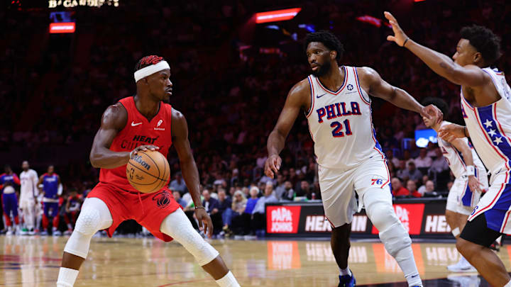 Nov 18, 2024; Miami, Florida, USA; Miami Heat forward Jimmy Butler (22) drives to the basket against Philadelphia 76ers center Joel Embiid (21) and guard Kyle Lowry (7) during the second quarter at Kaseya Center. Mandatory Credit: Sam Navarro-Imagn Images