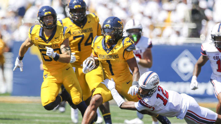 Aug 30, 2025; Morgantown, West Virginia, USA; West Virginia Mountaineers running back Jahiem White (1) runs the ball and is tackled by Robert Morris Colonials quarterback Jake Wolfe (12) during the first quarter at Milan Puskar Stadium. Mandatory Credit: Ben Queen-Imagn Images