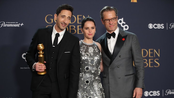 Jan 5, 2025; Beverly Hills, CA, USA; Adrien Brody, winner of best performance by a male actor in a motion picture drama for The Brutalist, with Felicity Jones and Guy Pearce at the 82nd Annual Golden Globe Awards at the Beverly Hilton Hotel in Beverly Hills, California on Sunday, Jan. 5, 2025. Mandatory Credit: Dan MacMedan-USA TODAY