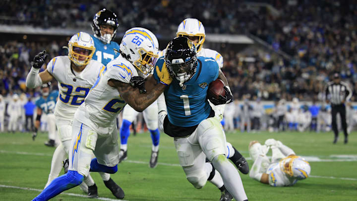 Jacksonville Jaguars running back Travis Etienne Jr. (1) rushes for yards against Los Angeles Chargers cornerback Asante Samuel Jr. (26) during the third quarter of an NFL first round playoff football matchup Saturday, Jan. 14, 2023 at TIAA Bank Field in Jacksonville, Fla. Jacksonville Jaguars edged the Los Angeles Chargers on a field goal 31-30. [Corey Perrine/Florida Times-Union]

Jki 011423 Chargers Jags C 54
