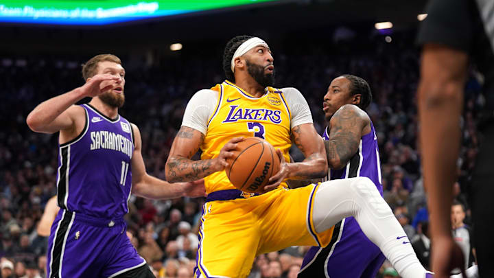 Dec 19, 2024; Sacramento, California, USA; Los Angeles Lakers forward Anthony Davis (3) holds onto the ball between Sacramento Kings center Domantas Sabonis (11) and guard DeMar DeRozan (10) in the second quarter at the Golden 1 Center. Mandatory Credit: Cary Edmondson-Imagn Images