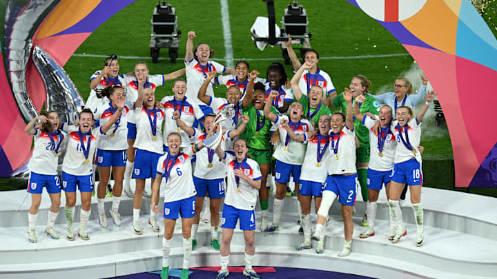 Leah Williamson and Keira Walsh hoist the Euro 2025 trophy for England.