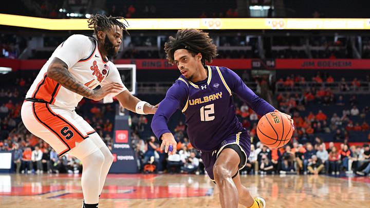 Dec 10, 2024; Syracuse, New York, USA; Albany Great Danes forward Justin Neely (12) drives the ball past Syracuse Orange center Eddie Lampkin Jr. (44) in the first half at the JMA Wireless Dome. Mandatory Credit: Mark Konezny-Imagn Images