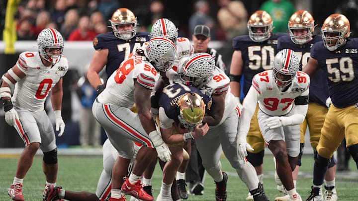 Jan 20, 2025; Atlanta, GA, USA; Notre Dame Fighting Irish quarterback Riley Leonard (13) is tackled by Ohio State Buckeyes defensive tackle Ty Hamilton (58) and Ohio State Buckeyes defensive tackle Tyleik Williams (91) in the CFP National Championship college football game at Mercedes-Benz Stadium. Mandatory Credit: Dale Zanine-Imagn Images
